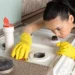 Drain snake tool placed next to a bottle of chemical drain cleaner on a tiled bathroom floor