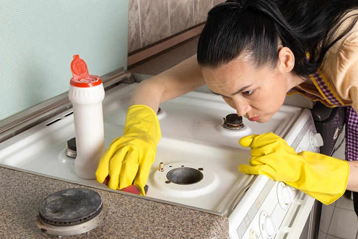 Drain snake tool placed next to a bottle of chemical drain cleaner on a tiled bathroom floor